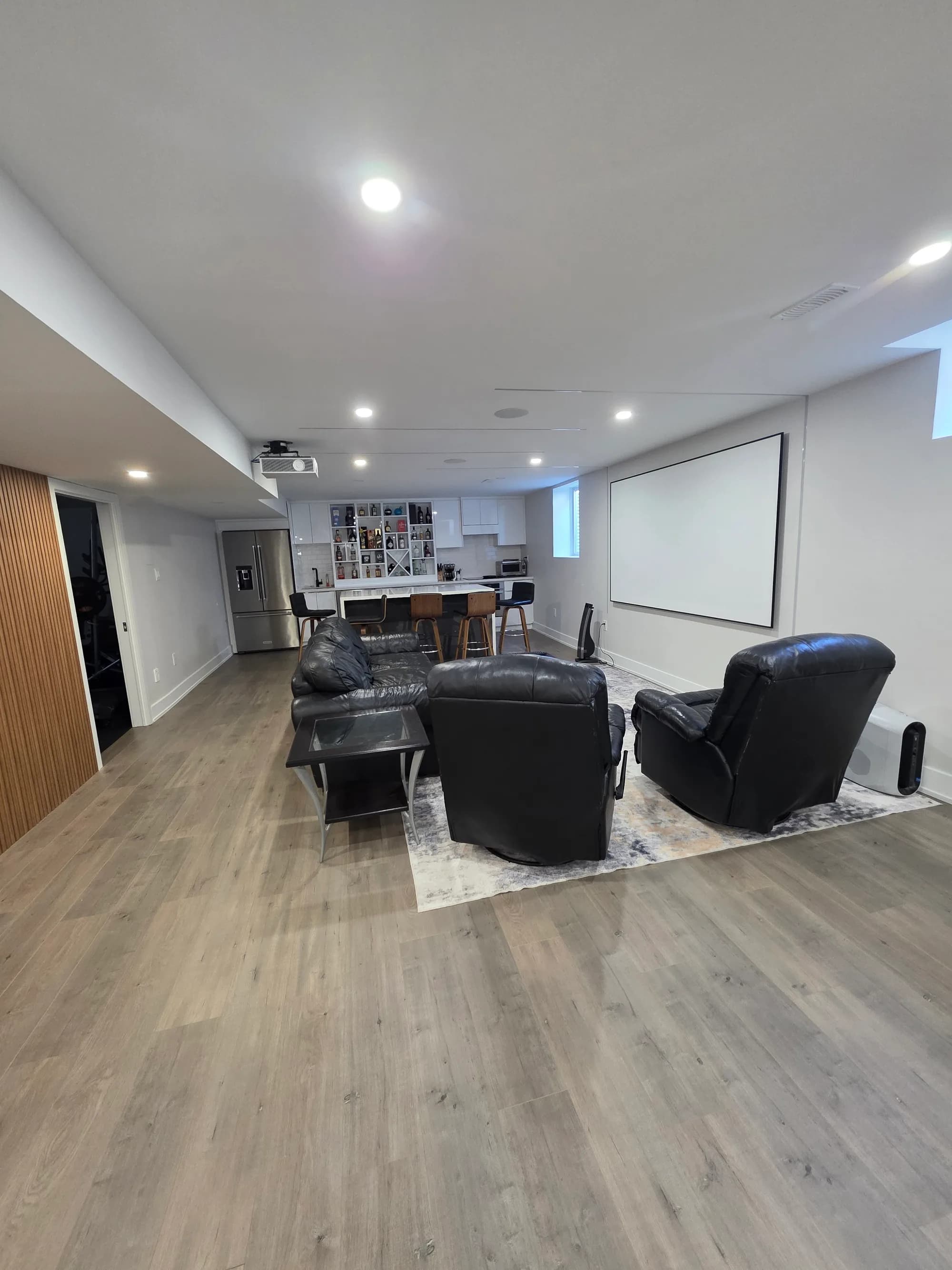 Basement with home theatre projector screen, open living area, and kitchen island