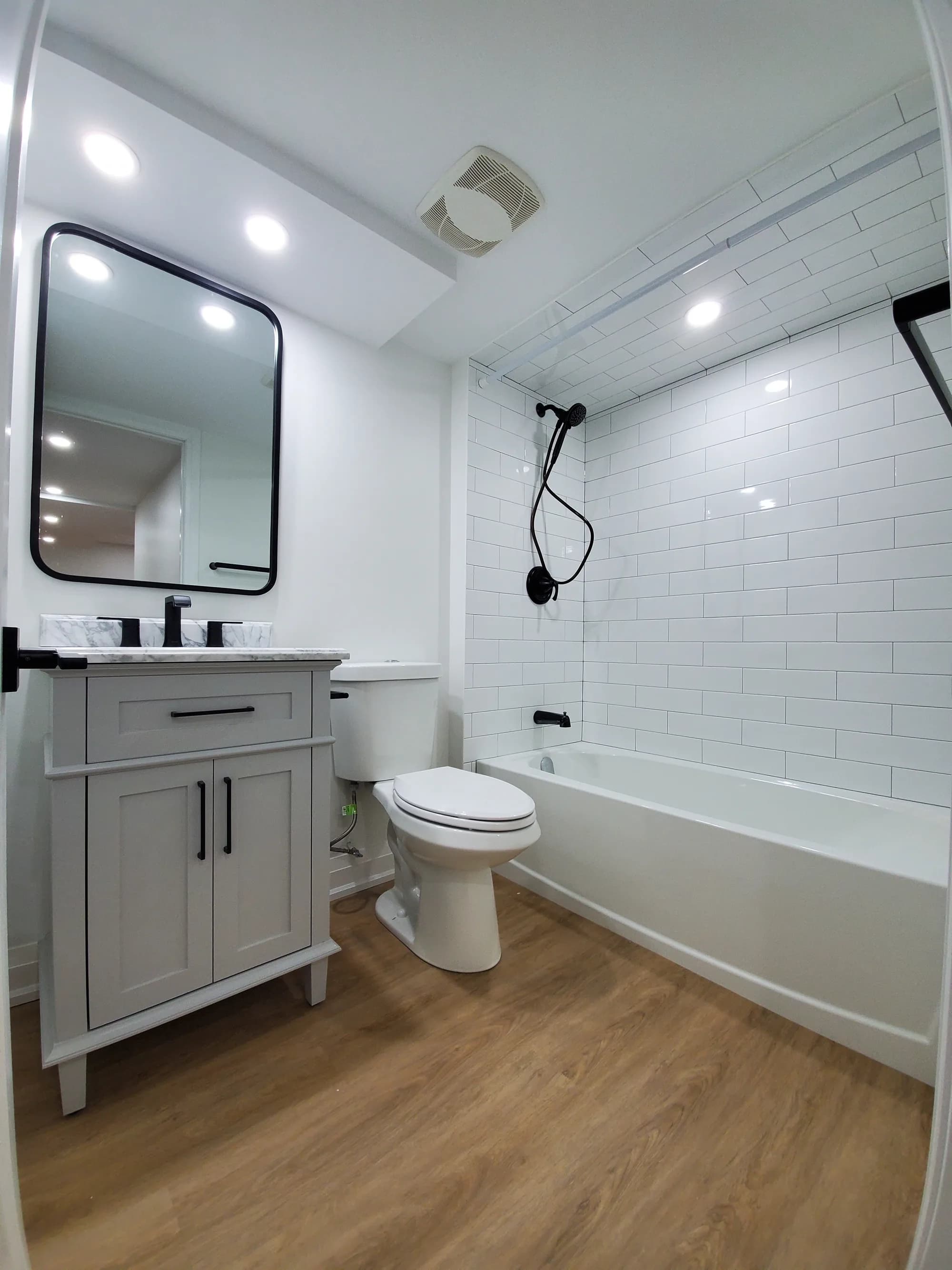 Basement bathroom with white subway tile, black fixtures, and grey shaker vanity