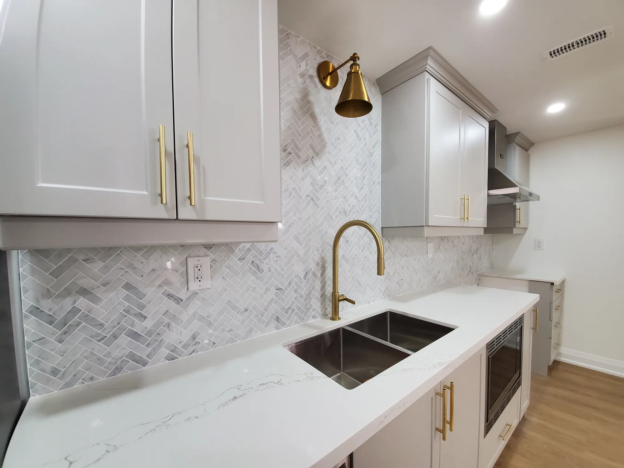Basement kitchen bar with marble herringbone backsplash and gold fixtures