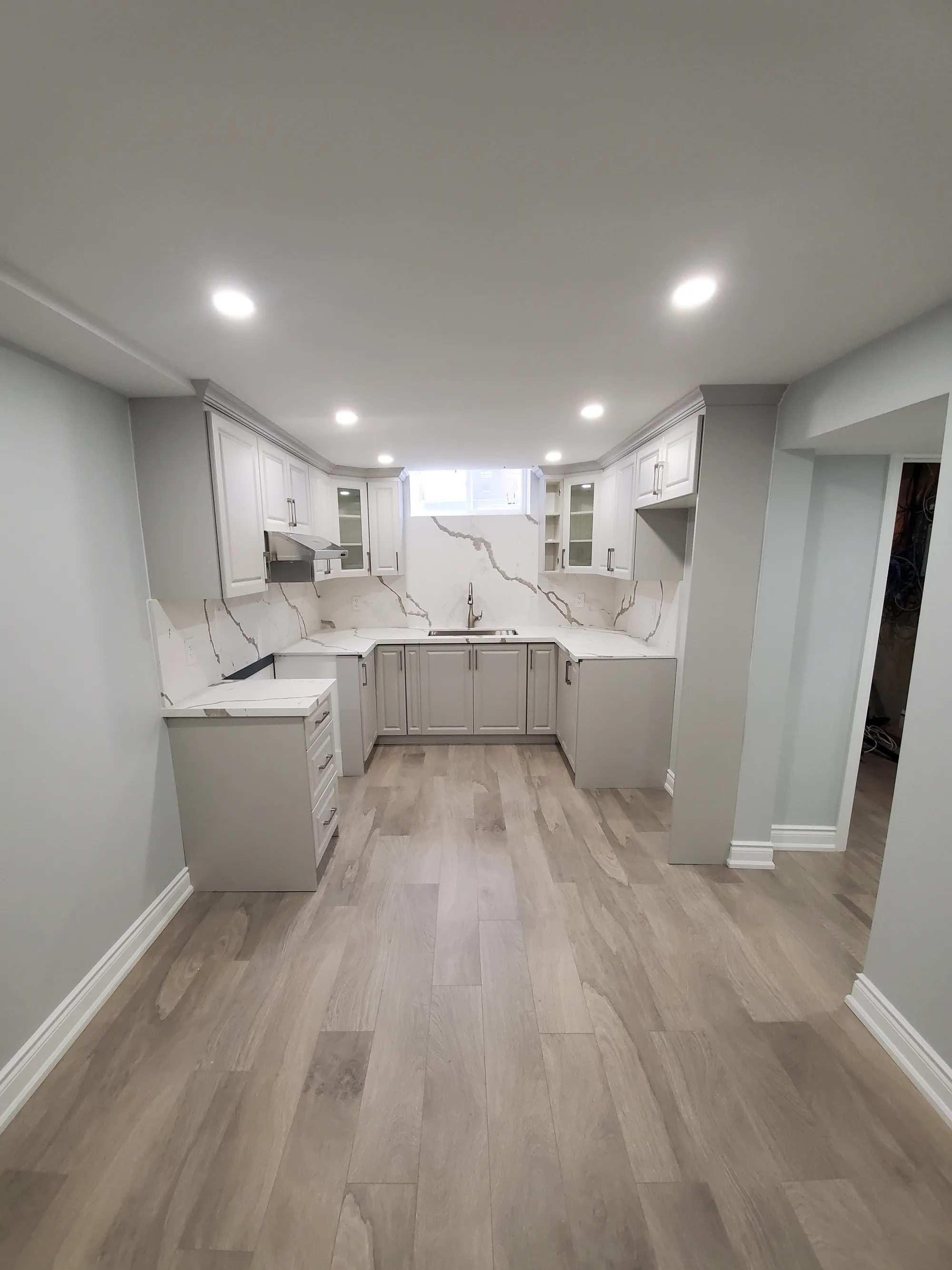 Basement kitchen with grey shaker cabinets and marble slab backsplash