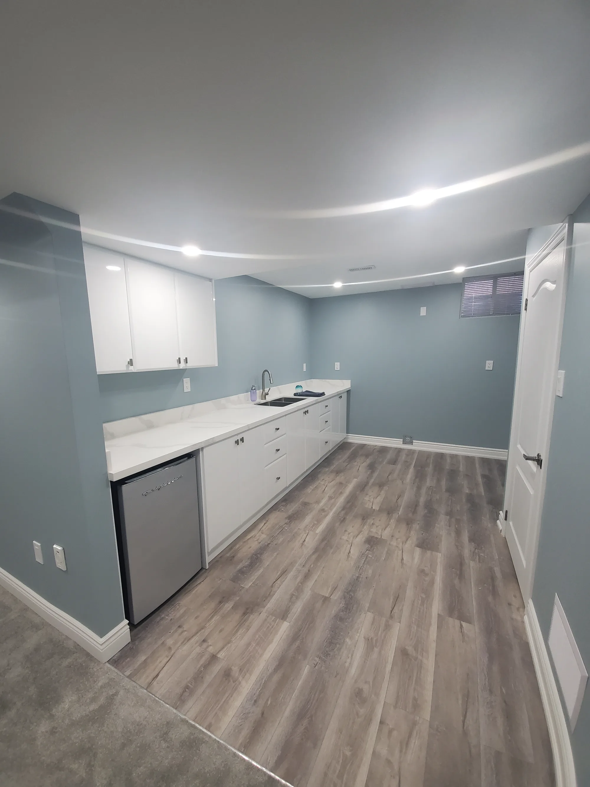 Basement suite with white flat-panel kitchen, quartz countertop, and mini fridge