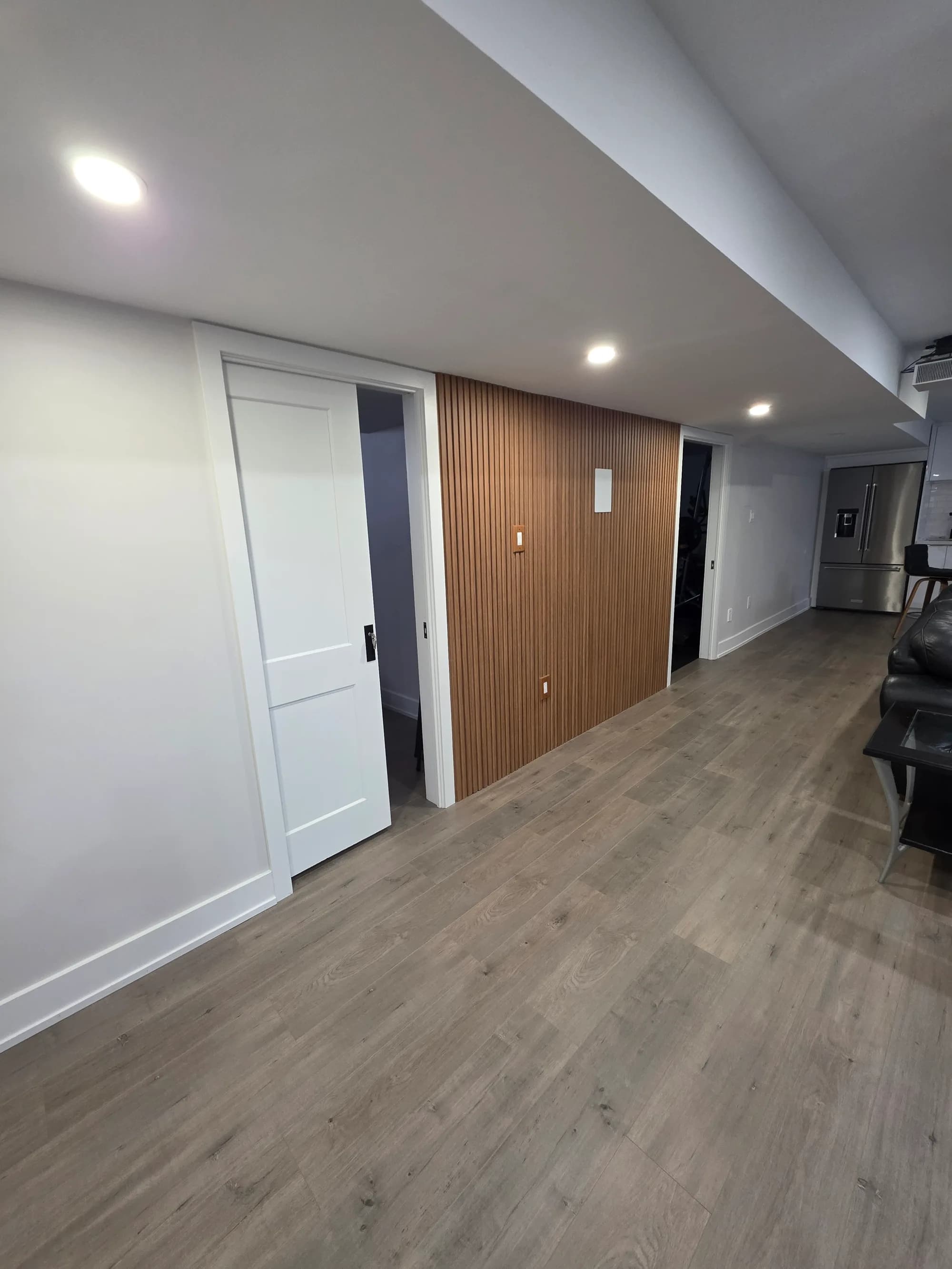 Modern basement hallway with wood slat accent wall and black hardware