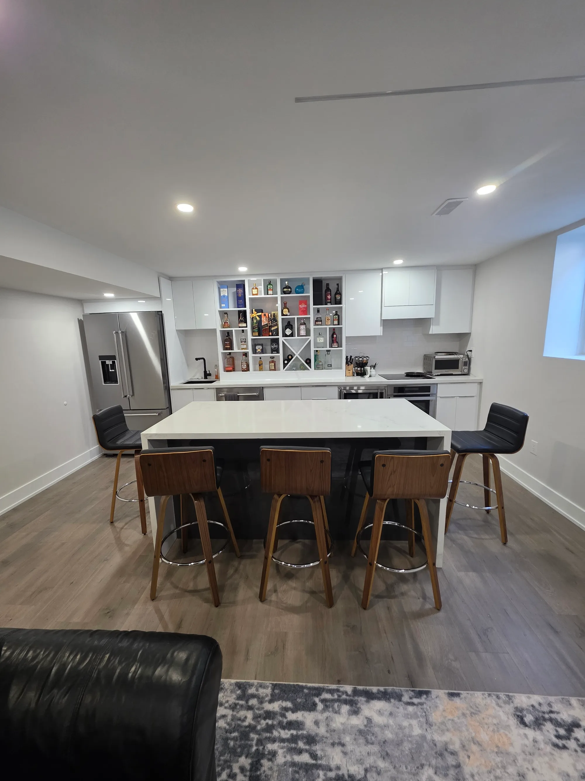 Modern basement kitchen island with bar stools and built-in bar shelving