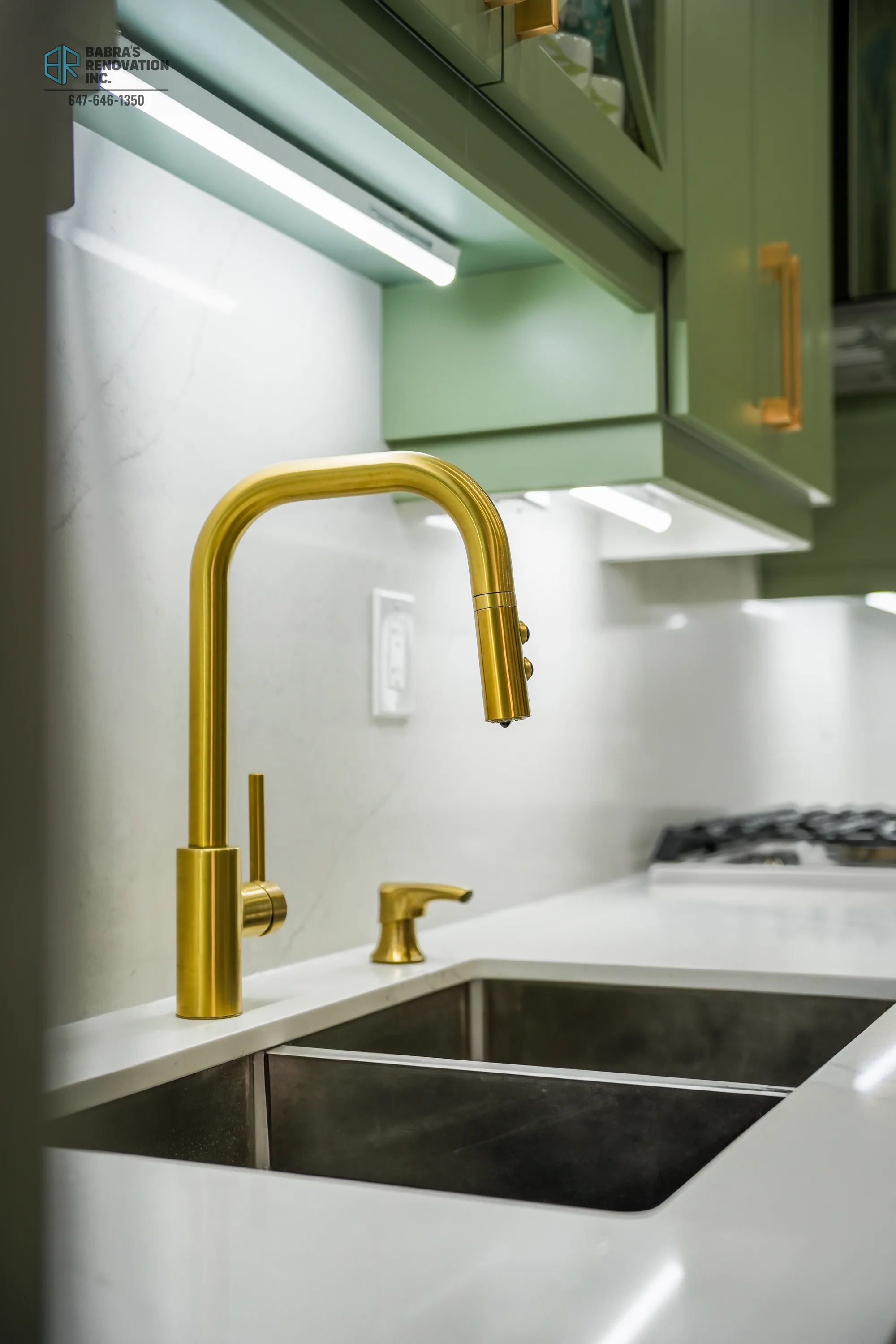 Close-up of gold faucet and sage green cabinets