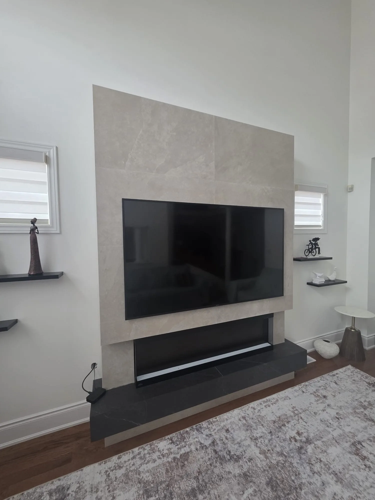 Stone-clad media feature wall with mounted TV, low fireplace bench, and floating display shelves
