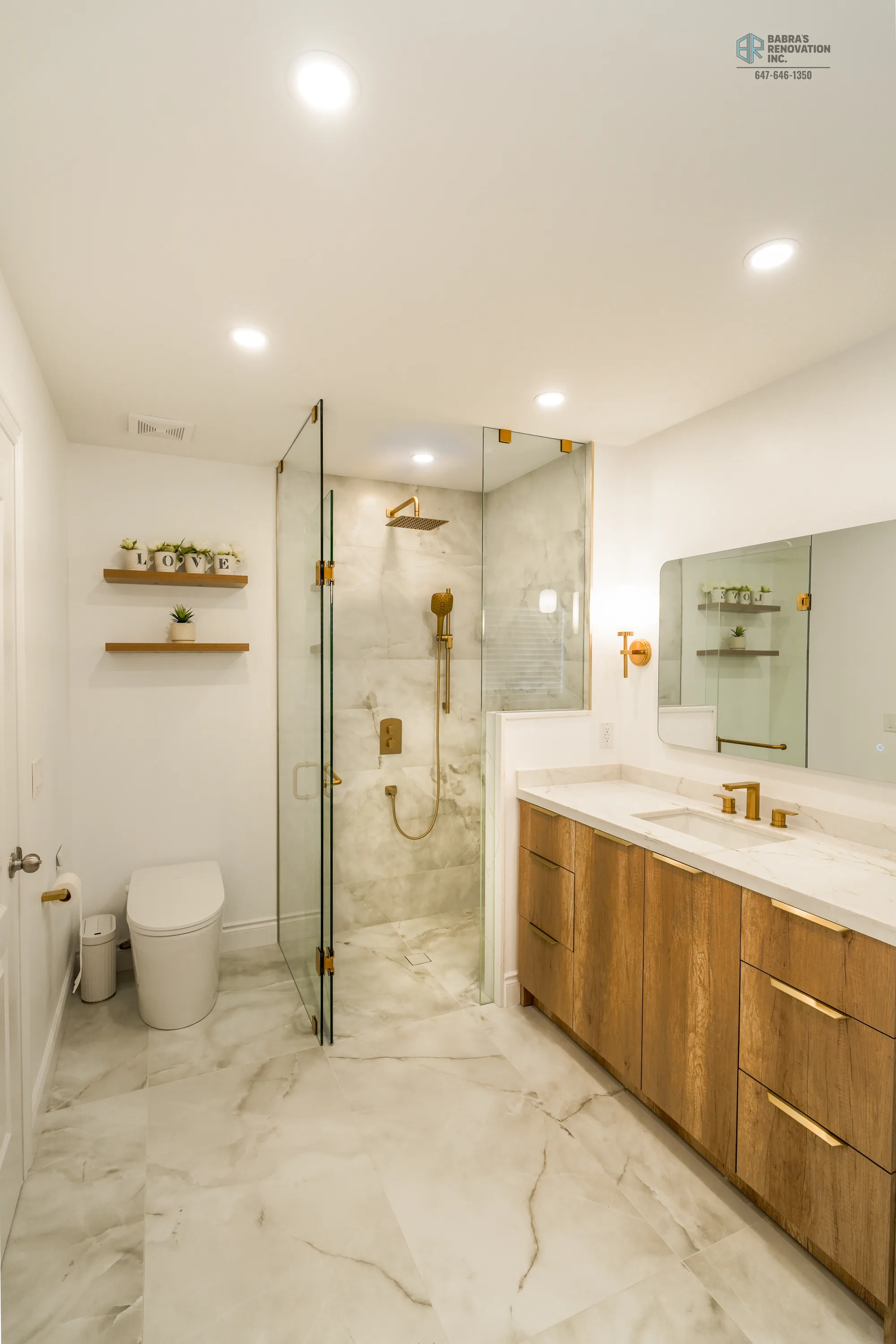 Renovated spa bath with walnut vanity, white marble walls, gold fixtures, and a frameless glass walk-in shower